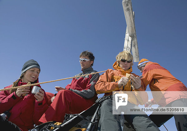 Gruppe von Skitourengehern bei Rast an Gipfelkreuz