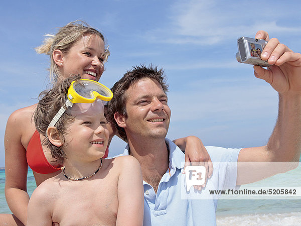 Eltern mit Sohn am Strand  Vater macht Foto