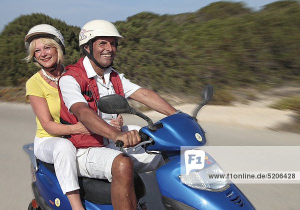 Älteres Paar fährt im Urlaub mit Motorroller