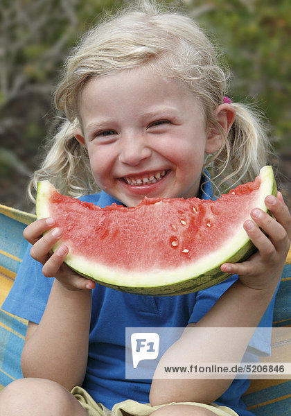 Kleines Mädchen isst Melone in Hängematte