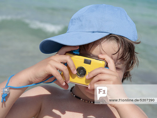 Kleiner Junge mit einfachem Fotoapparat am Strand  Porträt