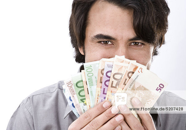 Mann hält Euroscheine vor sein Gesicht