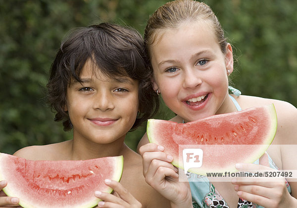 Mädchen und Junge mit Melonenstücken  Porträt