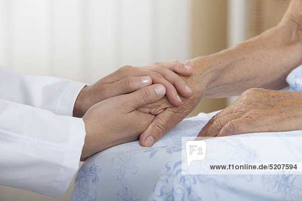 Hände halten Hand einer Seniorin