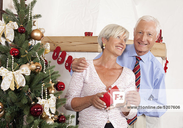 Seniorenpaar neben Weihnachtsbaum