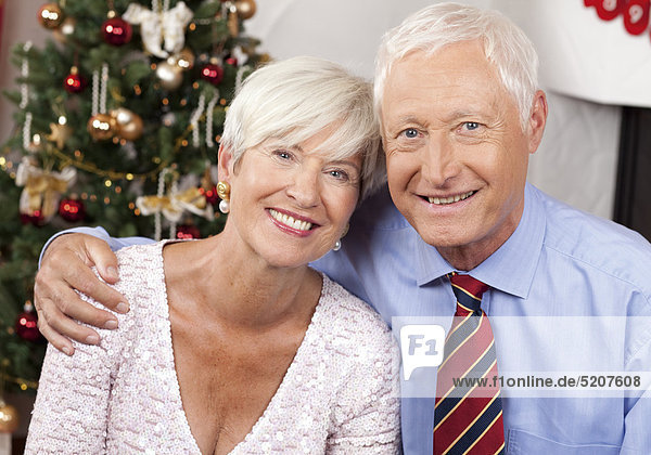 Seniorenpaar vor Weihnachtsbaum  umarmt  Porträt