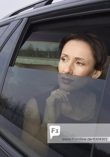 Frau schaut aus verdunkeltem Autofenster