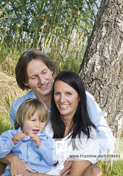 Familie sitzt unter Baum