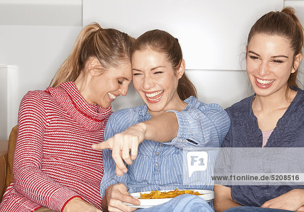 Drei junge Frauen vor dem Fernseher