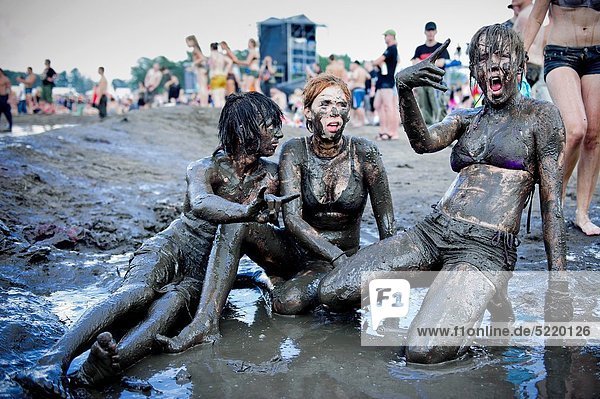 Young women having fun in the mud at the Przystanek Woodstock - Europe´s  largest open air festival in Kostrzyn, Poland