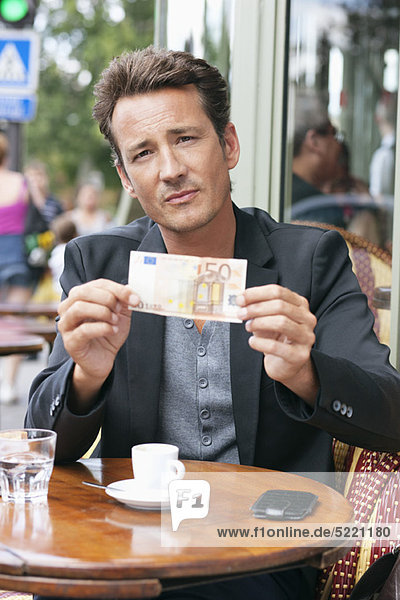 Man showing a 50 Euro banknote in a restaurant  Paris  Ile-de-France  France