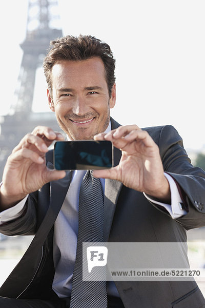 Businessman taking a picture of himself with the Eiffel Tower in the background  Paris  Ile-de-France  France