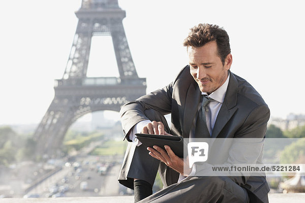 Geschäftsmann mit digitalem Tablett und Eiffelturm im Hintergrund  Paris  Ile-de-France  Frankreich