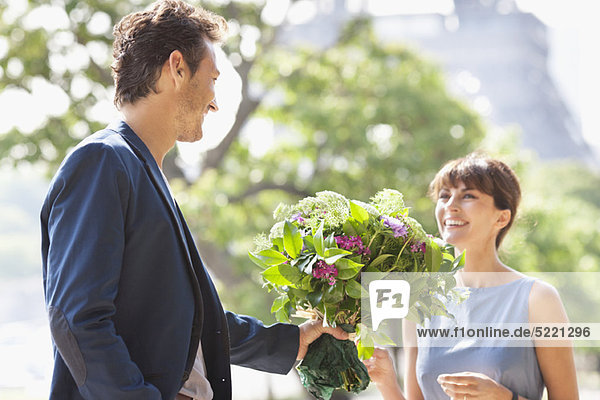 Mann schenkt einer Frau einen Blumenstrauß mit dem Eiffelturm im Hintergrund  Paris  Ile-de-France  Frankreich