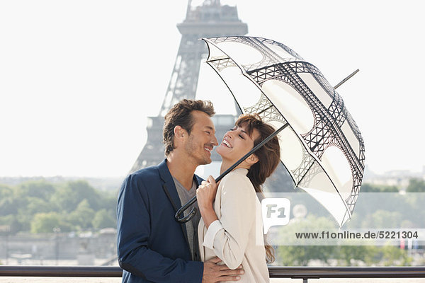 Paar unter einem Schirm mit dem Eiffelturm im Hintergrund  Paris  Ile-de-France  Frankreich