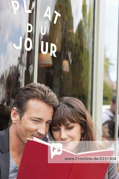 Couple reading menu at a restaurant,  Paris,  Ile-de-France,  France