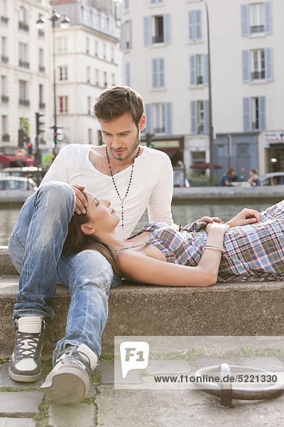 Woman lying on lap of a man at the ledge of a canal  Paris  Ile-de-France  France