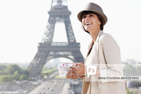 Woman holding a guide book with the Eiffel Tower in the background  Paris  Ile-de-France  France