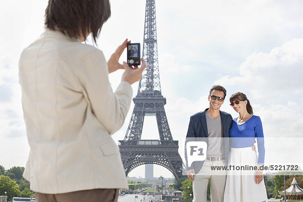 Frau beim Fotografieren eines Paares mit dem Eiffelturm im Hintergrund  Paris  Ile-de-France  Frankreich