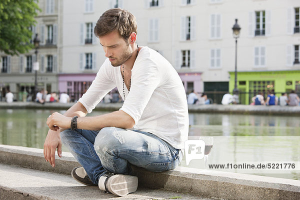 Mann sitzt am Rand eines Kanals und denkt nach  Paris  Ile-de-France  Frankreich