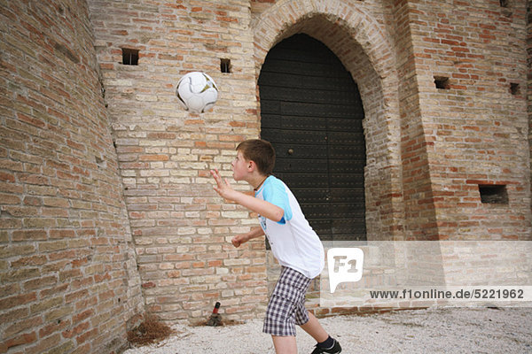 Boy Practicing With Football In Street