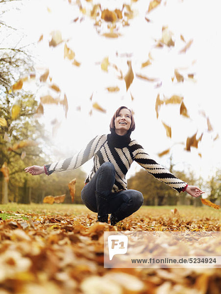 A woman looking up as autumn leaves fall