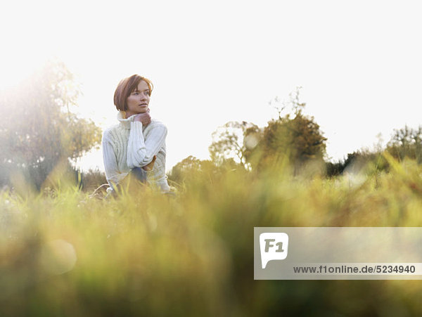 A woman sitting in the grass  looking away  low angle view