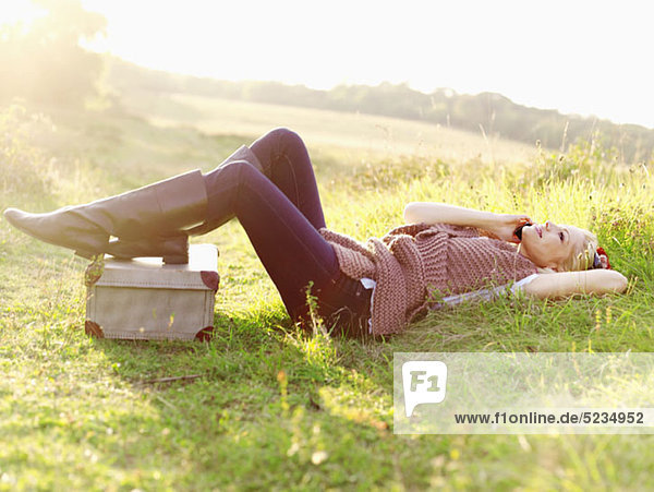 A woman lying in grass using a mobile phone
