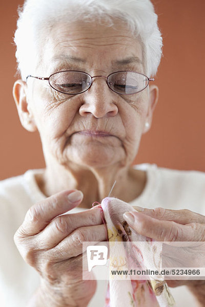 A senior woman stitching fabric