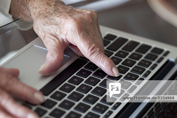 Detail einer älteren Frau  die einen Laptop benutzt.