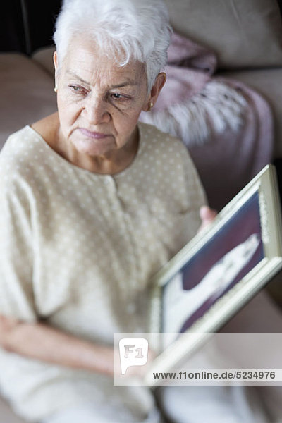 Eine ältere Frau  die einen Bilderrahmen hält.