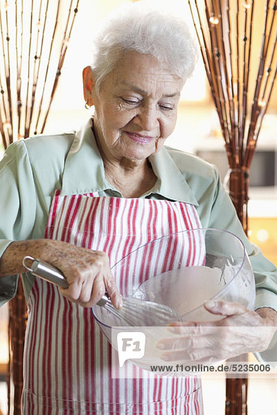 Eine ältere Frau mischt Zutaten in einer Schüssel
