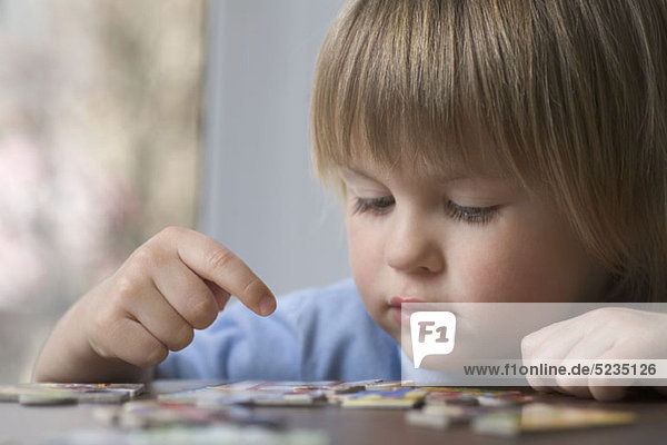 Ein kleiner Junge  der ein Puzzle zusammenstellt.