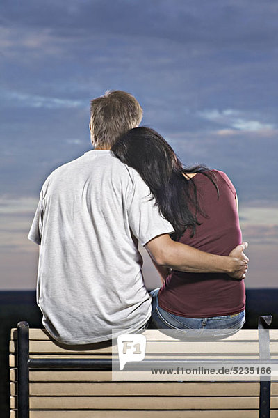 Ein Paar sitzt auf einer Bank und beobachtet den Sonnenuntergang.