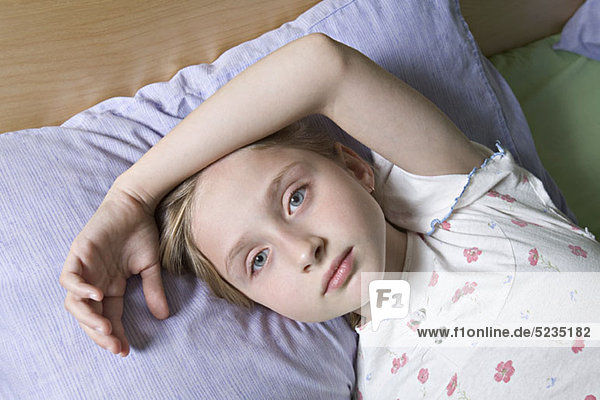 A girl lying on a bed  looking at camera
