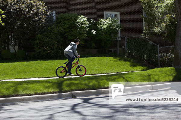 Junge steht beim Radfahren auf dem Fußweg