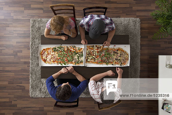 Vier Freunde machen sich bereit  zwei große Pizzen zu essen  Blick nach oben