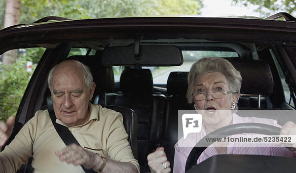 Frau  die das Fahren lernt  wird aufgeregt  während der Mann auf dem Beifahrersitz zur Ruhe kommt.