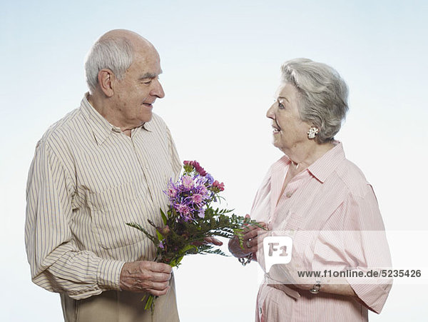 Senior Mann schenkt Seniorin Blumen