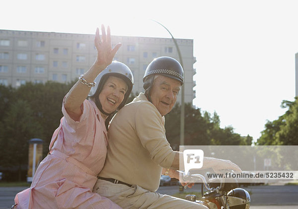 Seniorenpaar glücklich auf dem Motorrad als Frau winkt