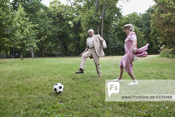 Senior Mann und Frau spielen Fußball im Park.