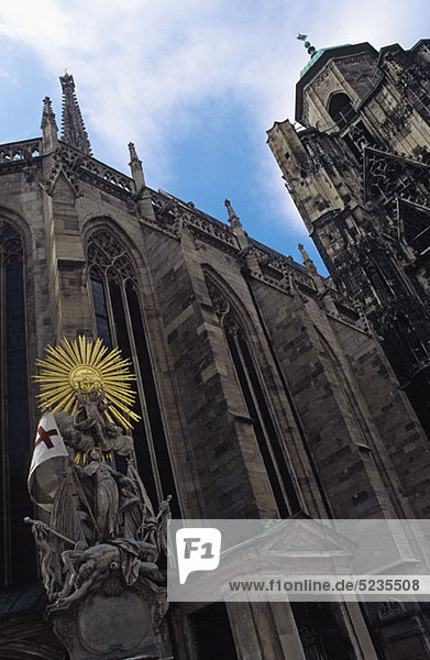 Österreich,  Wien,  Stephansdom mit Statue des hl. Franziskus unter der Sonne im Vordergrund