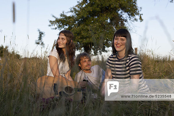 Three friends amongst the timothy grass with wine and guitar