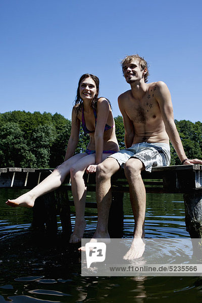 Paar nebeneinander auf Steg tauchende Füße im See