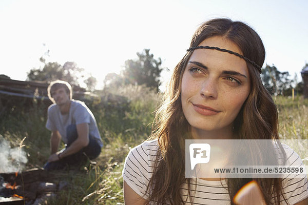 Profile of Long haired girl in field  and guy in the background looking at her