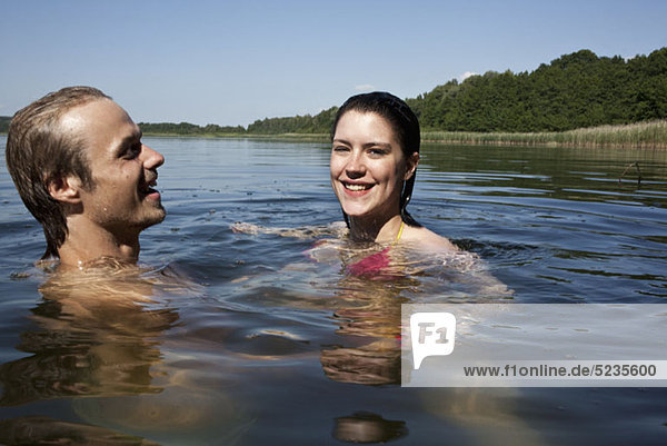 Mann und Frau schwimmen glücklich im See