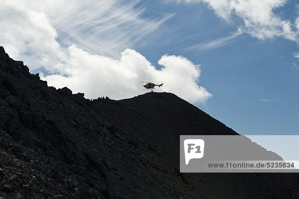 The Wetterstein  Tirol  Austria  Helicopter in distance above a silhouetted mountain