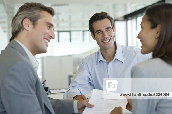 Smiling couple discussing contract with adviser