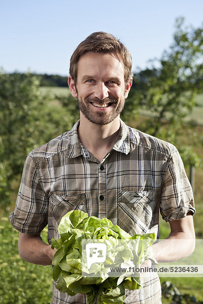 Mann mit Salatkopf im Freien