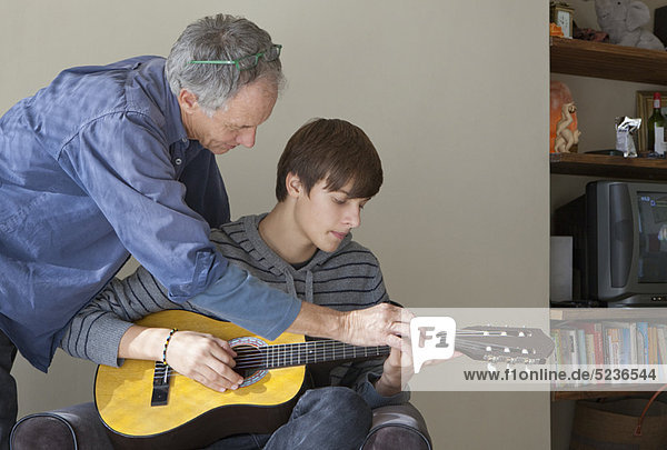 Father helping son play guitar